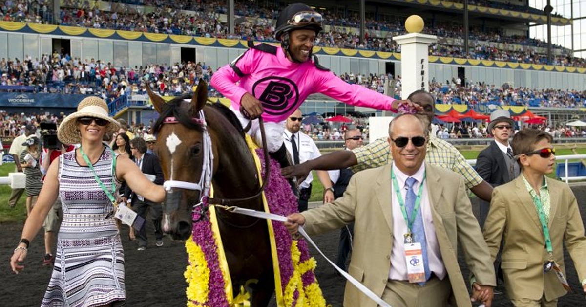 Jockey Patrick Husbands plants the flowers on trainer Mark Casse as they walk Lexie Lou into the winner's circle after capturing the 2014 Queen's Plate Stakes.