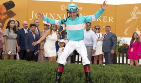 A jockey leaping in the air in the winners circle.