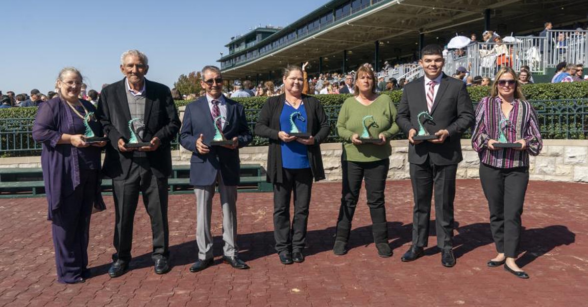 A group of people standing trackside with awards.