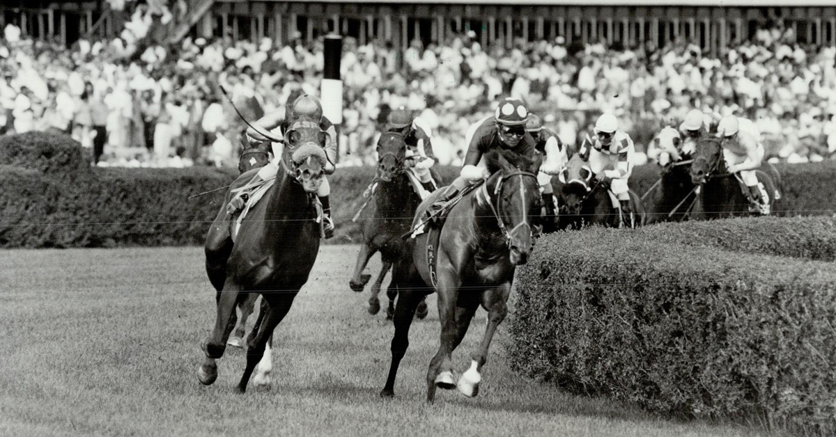 Black-and-white photo of horses racing.