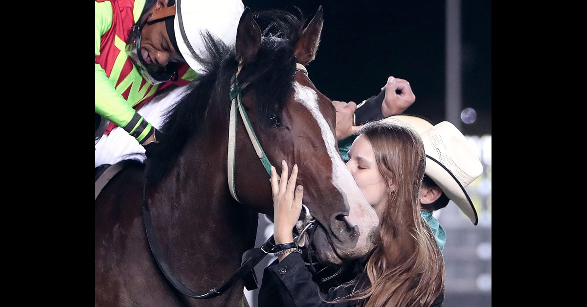 A woman kissing a horse.