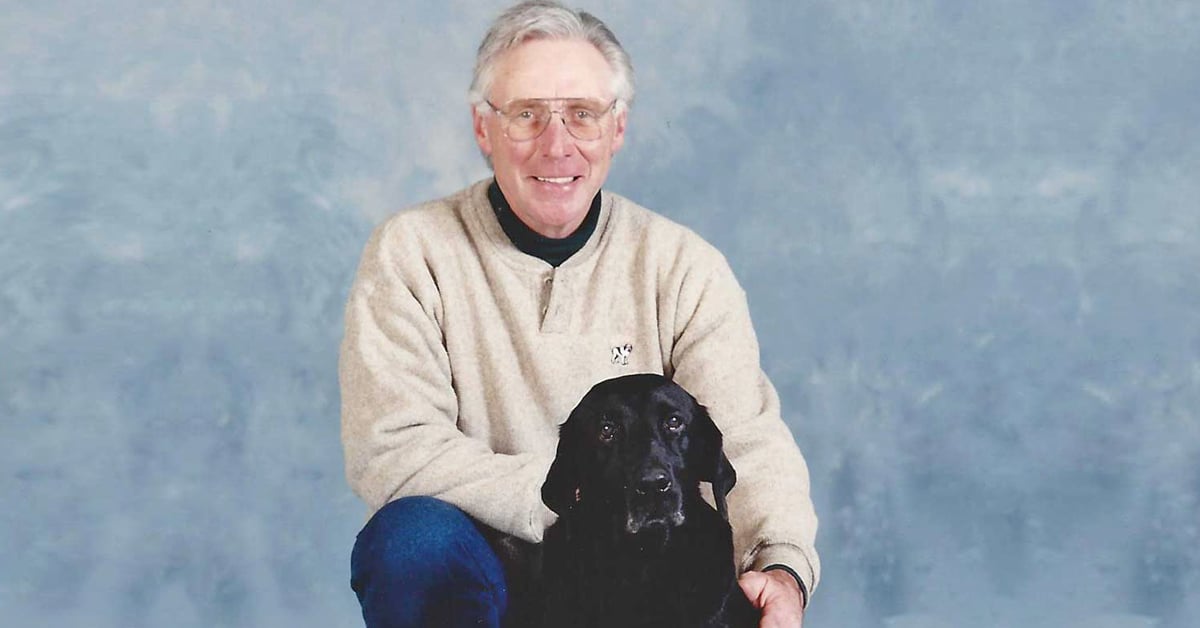 Dr. Norm Elder sitting with a black dog.