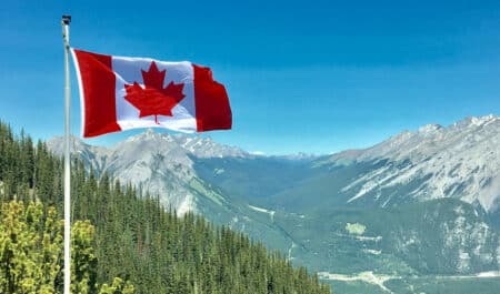 A Canadian flag with the Rocky Mountains in the background.