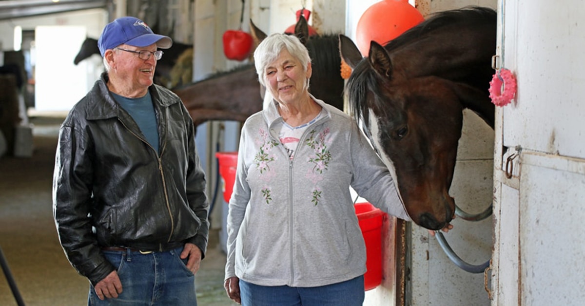 A man and woman in a racing barn.
