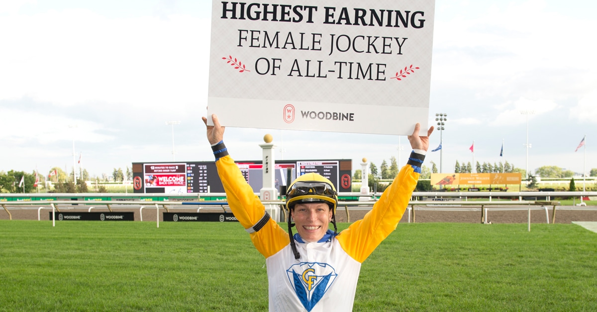 A female jockey holding up a sign at Woodbine.